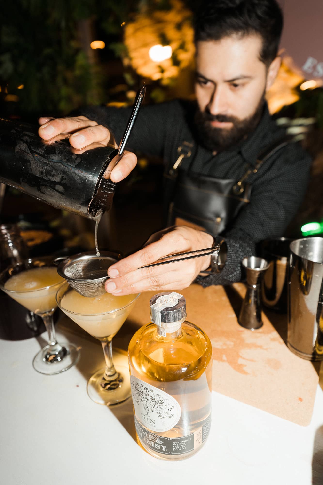 A bartender double-straining a cocktail at a Costa Spirits event